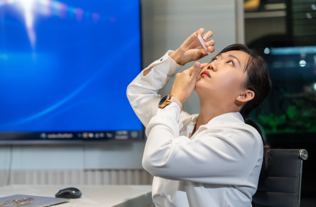 A professional-looking woman applying artificial tears on her right eye.