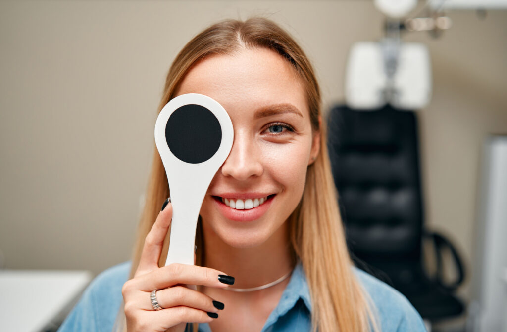 A woman using an occluder to block the vision on her right eye as a part of a visual acuity test.